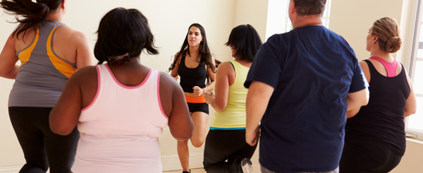 A group of ethnically diverse adults take part in an indoor exercise class