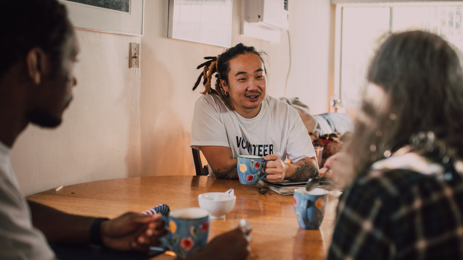 A group of men and woman who volunteer sit around a table and have a chat